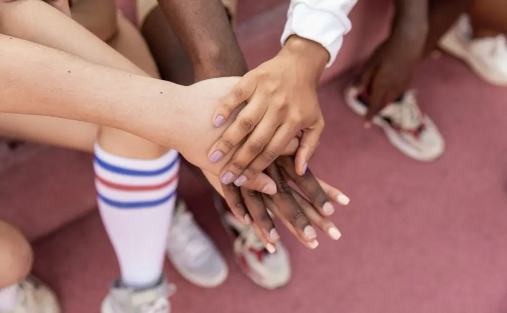 faceless multiracial sport team stacking hands on court