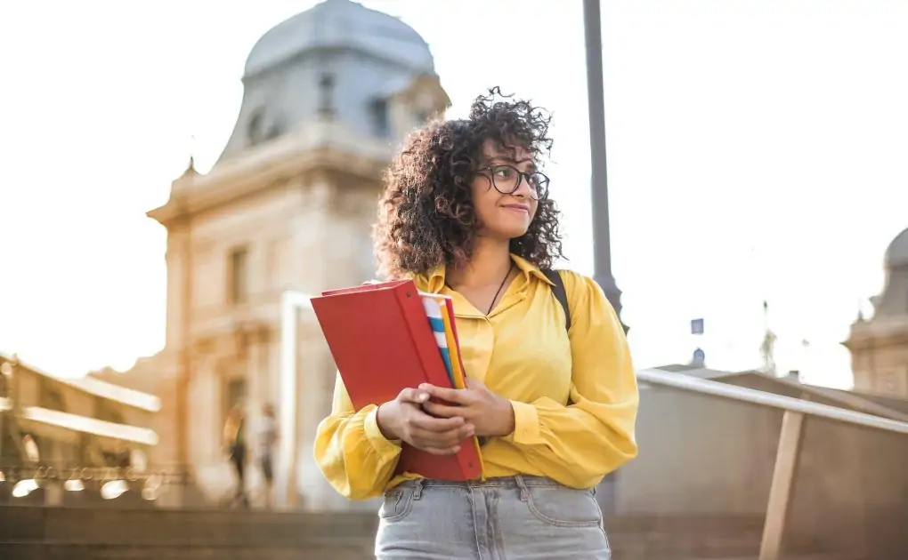 woman in yellow jacket holding books