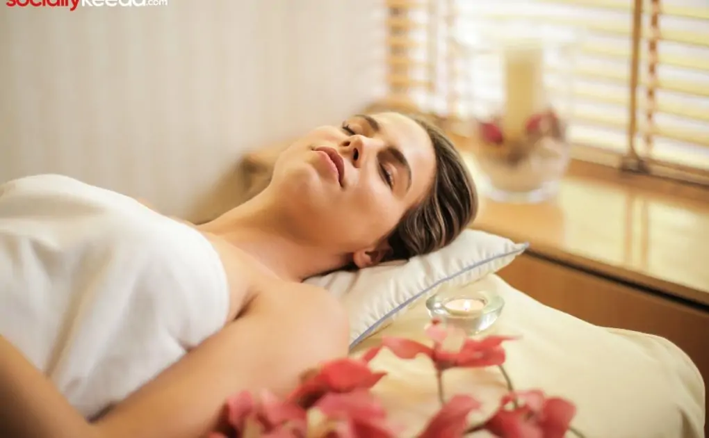 woman in wrapped in white towel lying on bed with eyes closed
