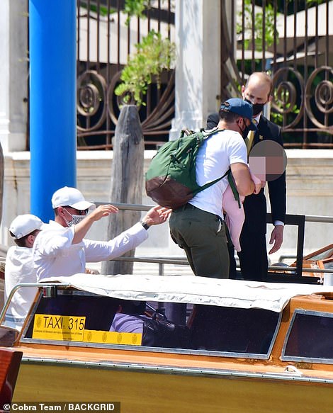 Drop off: Orlando held on to his daughter as he stepped off the boat, a green backpack over one shoulder