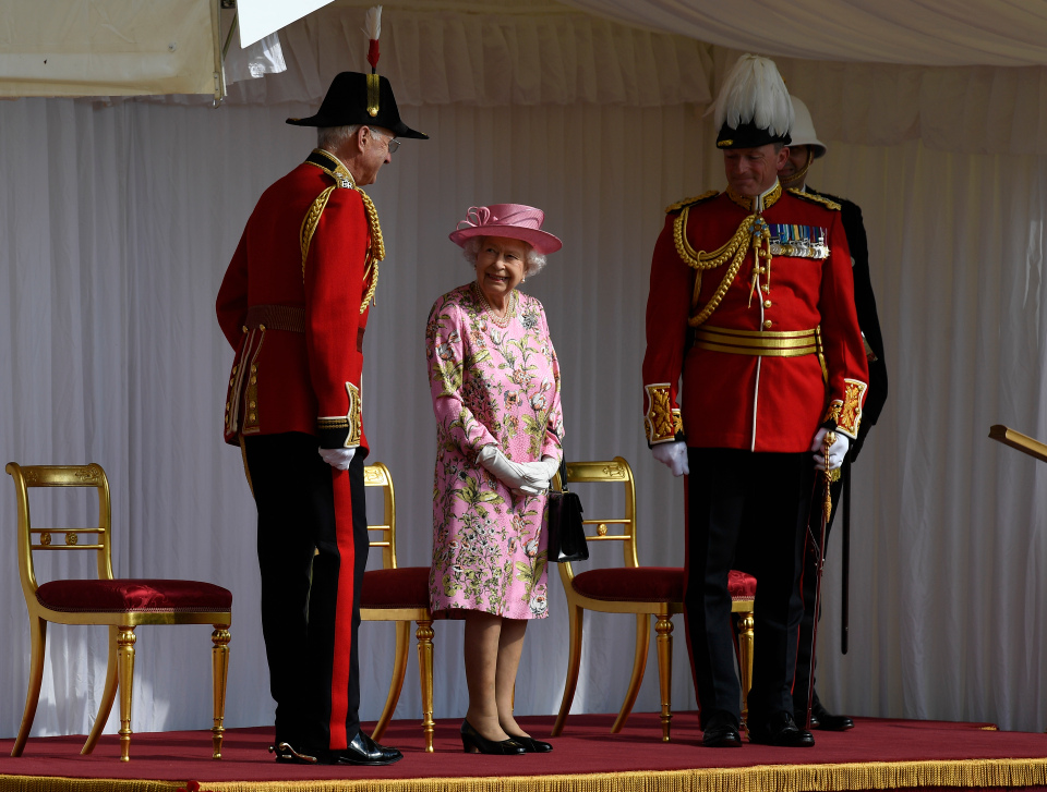 The Queen, who wore pink for the meeting, was flanked by guards as she awaited the Bidens' arrival