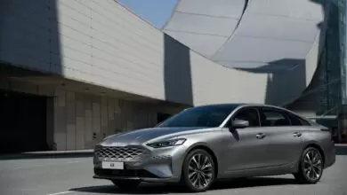 Silver Car Parked In Front Of Futuristic Building